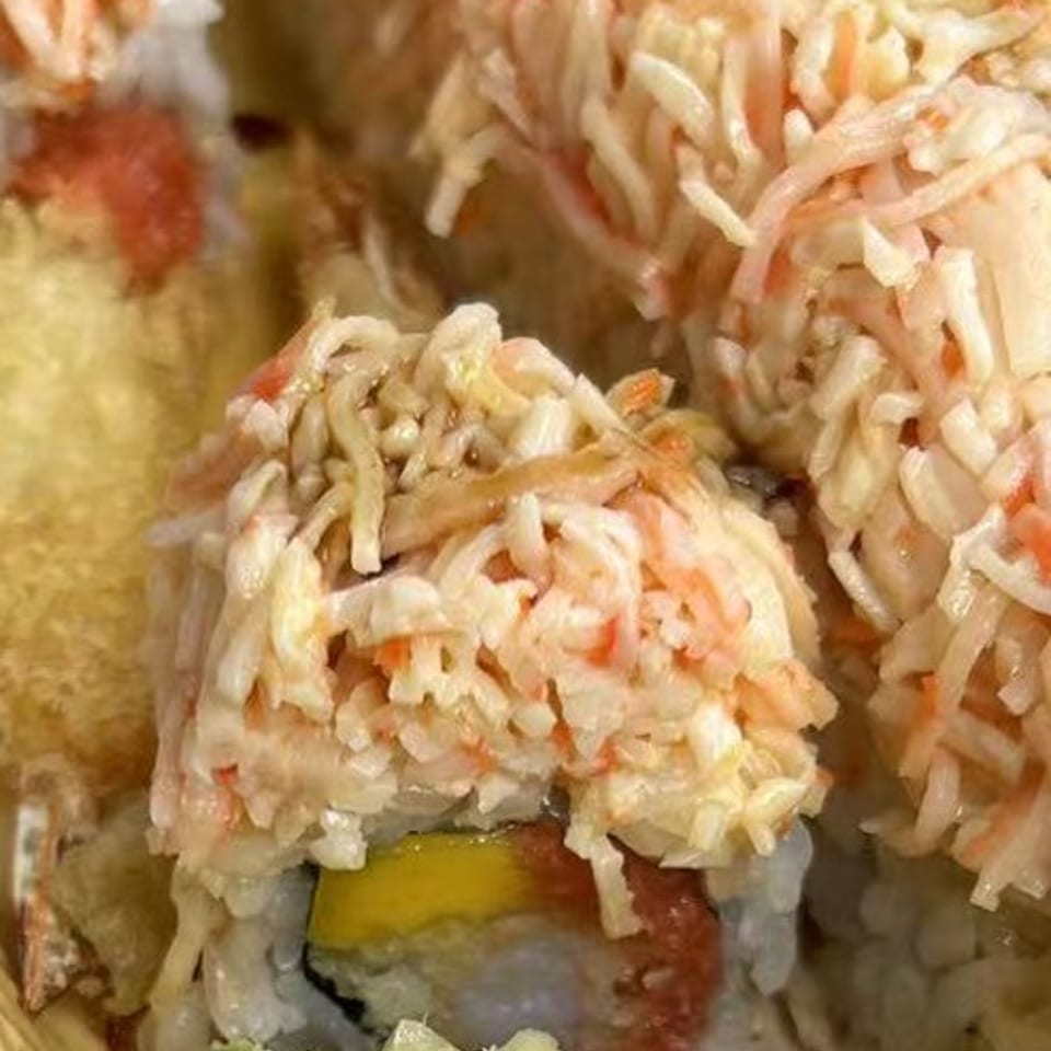 Close-up of sushi rolls topped with shredded crab, showing mango, tuna, wasabi, and ginger.